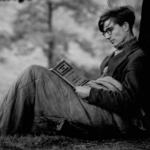 A man under a tree reading a book.