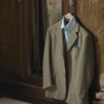 A suit hanging from a door knob by a hanger.